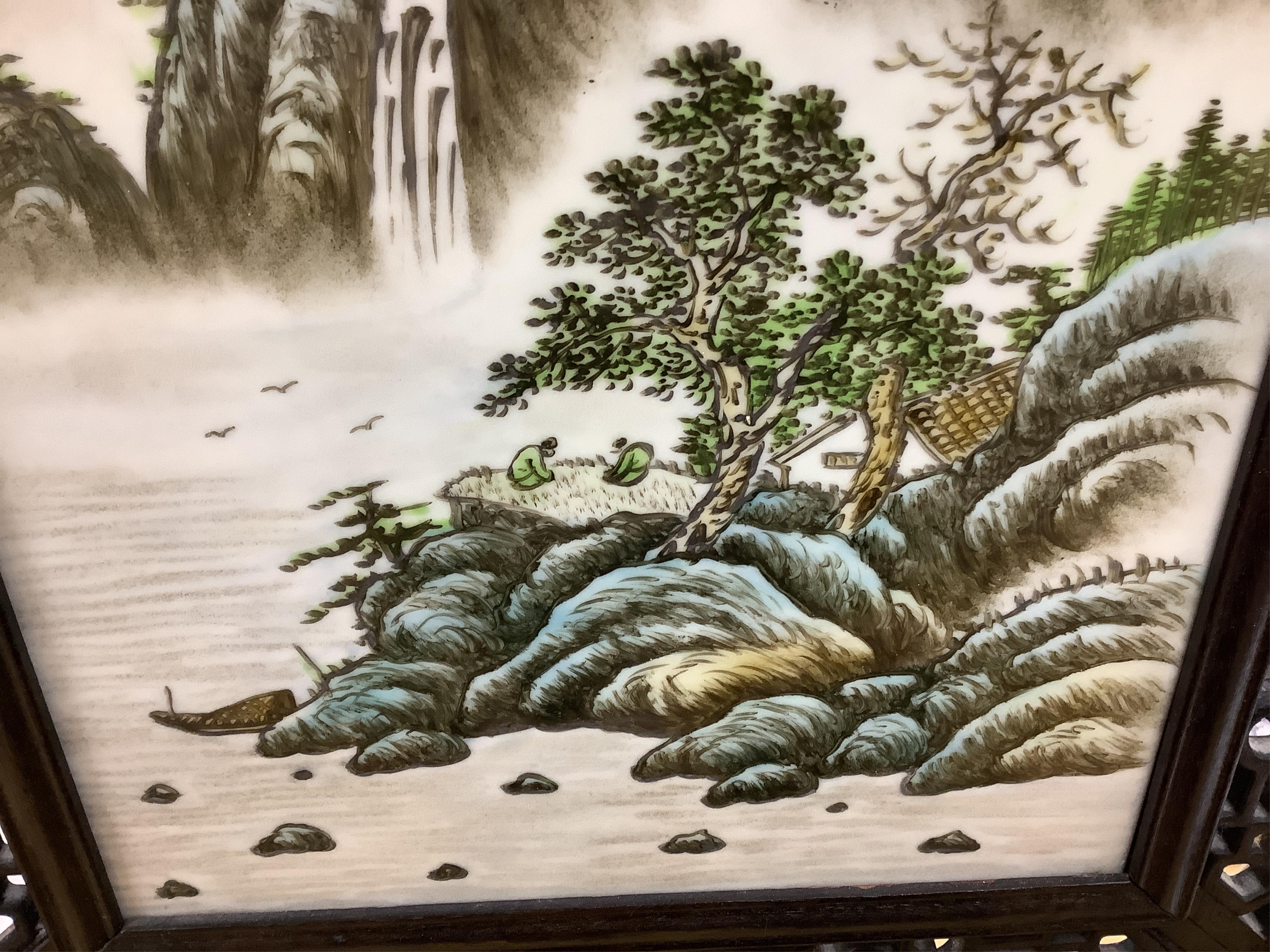 A Chinese carved table screen with a famille rose central plaque, screen 66cm high, plaque 35cm high. Condition - good